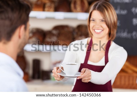 Bakery shopkeeper gives coffee to customer at the bread store