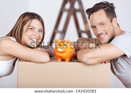 Conceptual portrait of new couple with piggybank on top of the box Conceptual portrait of new couple with piggybank on top of the box