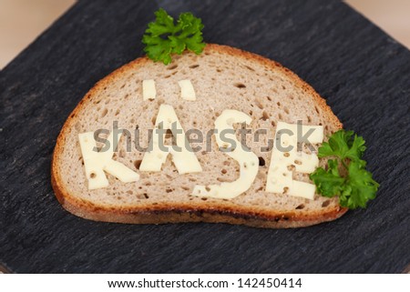 Slice of bread with the Cheese word written in the German language made with real cheese over a stone slab