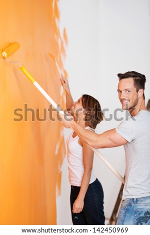 Portrait of loving couple painting wall of their new house