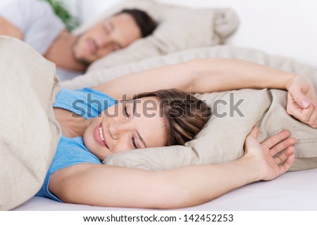 Young Woman Lying In Bed Awakening From A Sleep Stretching And Smiling