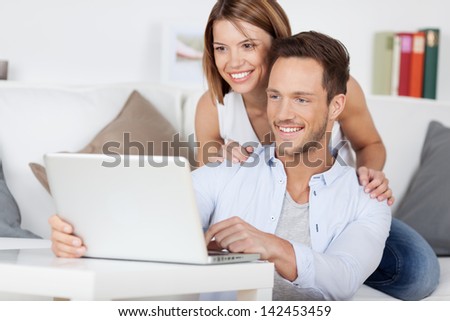 Cheerful couple searching something on laptop at home