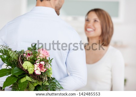 Young man hides a bouquet of flowers behind his back