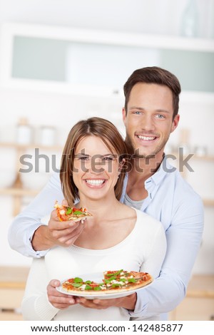 Young in love couple eating pizza in the kitchen