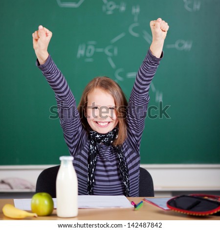 Smiling student raising her hands at the classroom