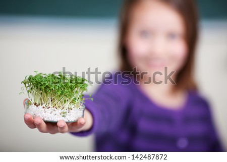 Female student showing a petri dish with little plants