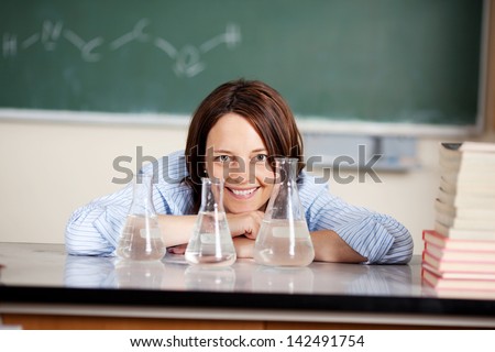Portrait of a happy young teacher with test tubes in a classroom