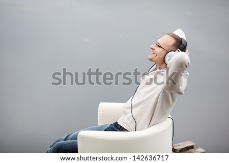 Portrait of mature man listening musing through headphones on pier