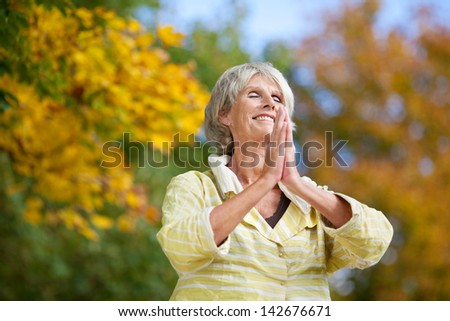 Low angle view of senior woman with hands clasped meditating in park