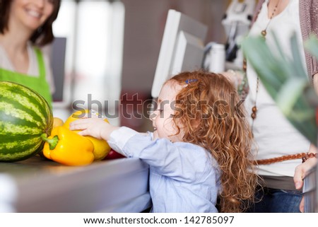 Cute Little Girl Buying Groceries Placing The Fresh Fruit On The Counter At The Checkout