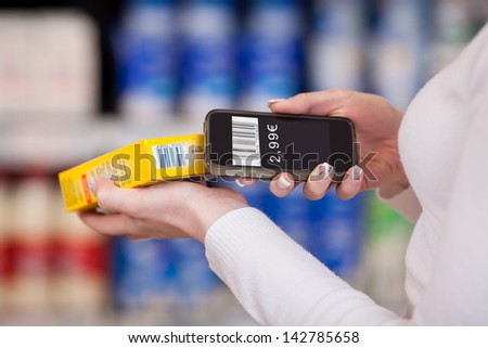 Closeup of woman\'s hands scanning barcode with mobile phone in supermarket