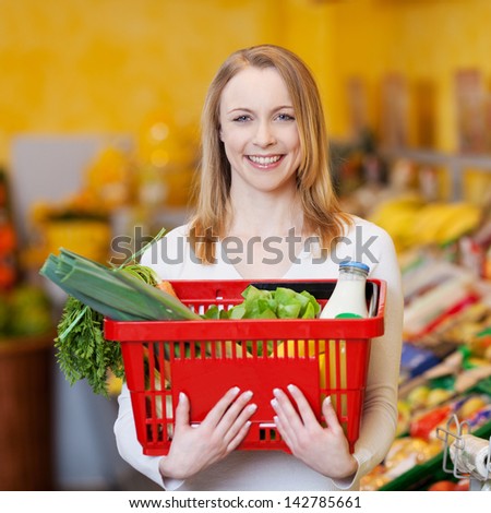 Portrait of happy beautiful woman carrying shopping basket in grocery store