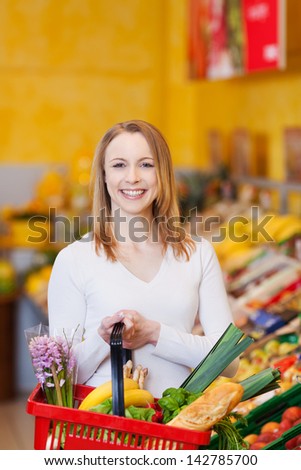 Portrait happy young woman carrying shopping basket in grocery store