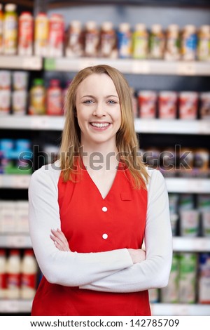 Portrait of beautiful saleswoman with arms crossed standing in grocery store
