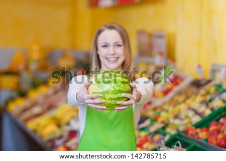 Portrait of happy female worker holding watermelon in grocery store