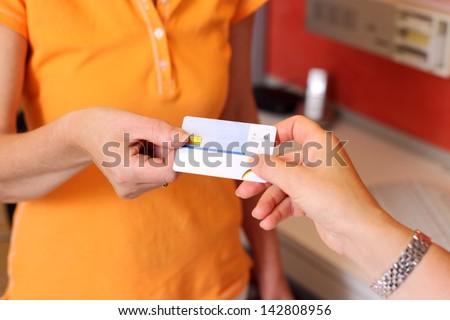 Closeup of client\'s hand giving ID card to dentist in clinic