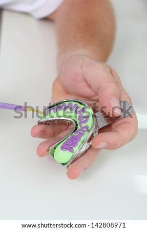 Closeup of dentist\'s hand preparing teeth impression tool on table