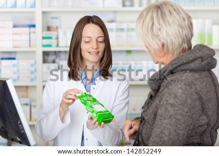 Female pharmacist explaining product details to customer in pharmacy