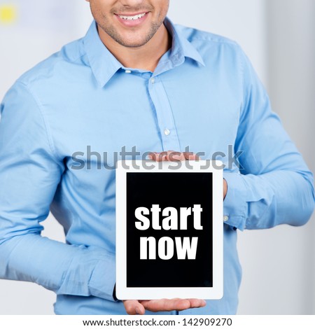 Midsection of businessman holding digital tablet with Start Now sign in office