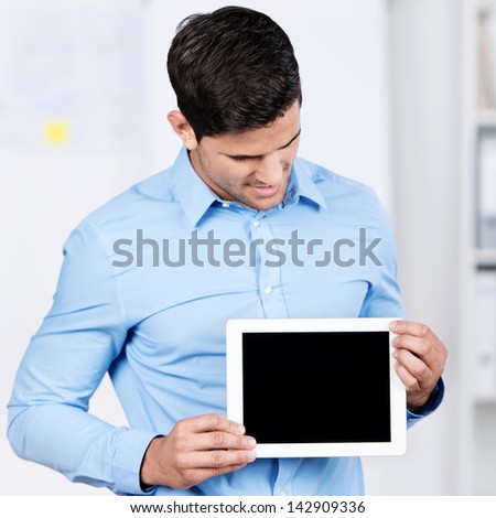 Young businessman holding digital tablet while looking at it in office