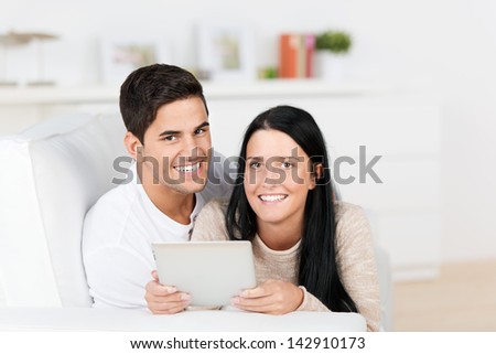 Portrait of happy young couple using digital tablet together on sofa at home