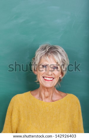 Portrait of happy senior female teacher against chalkboard