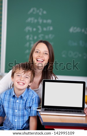 Happy teacher and student learning from laptop in the classroom
