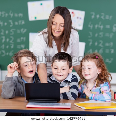Portrait Of Children And Teacher Looking At Laptop In The Classroom