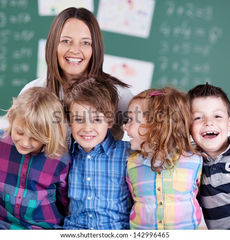 Portrait of teacher in classroom with his laughing students in the classroom