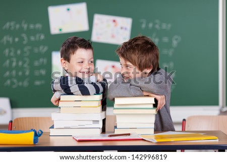 Two male friends studying with a pile of books on the table