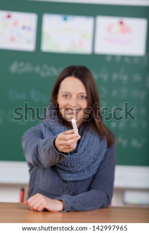 Happy teacher giving chalkboard to someone in the classroom