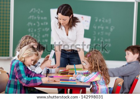 Portrait of teacher helping her busy students in art class
