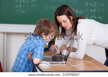 Teacher teaching elementary student from laptop in the classroom