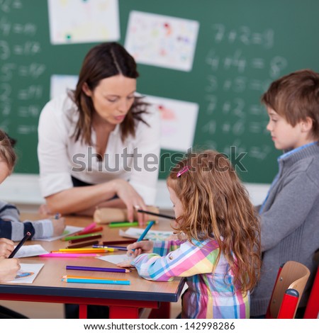 Portrait of teacher helping her busy students inside the classroom