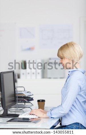 Side view of a young businesswoman using computer at office desk