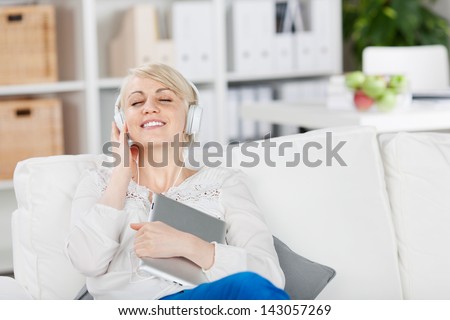 smiling woman enjoying music from digital pad