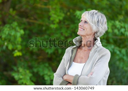 Happy senior woman looking at the beautiful trees