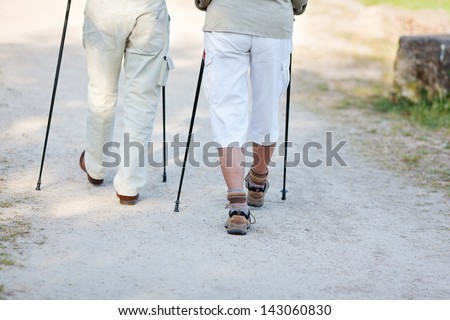 Elderly couple traveling with nordic walking sticks, walking together.