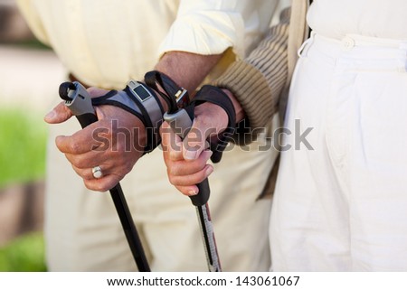 Closeup of senior couple\'s hands holding hiking poles