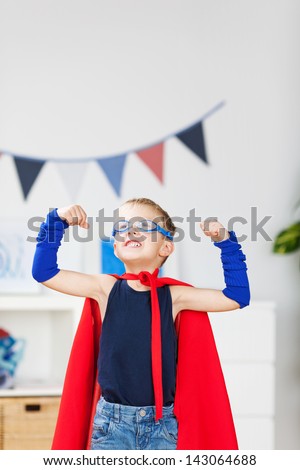 Strong kid wearing a superhero costume and showing his muscle