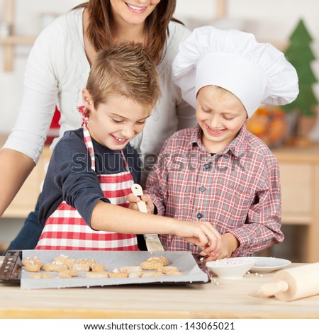 Happy brothers and mother baking cookies together at kitchen counter