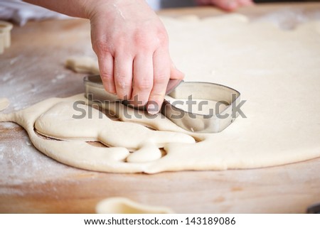Closeup view of a female hand cutting out Easter rabbit biscuits with a pastry cutter