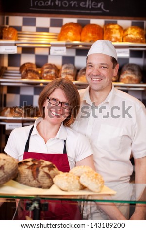 Friendly bakery staff standing behind the counter in a modern bakery with well stocked shelves