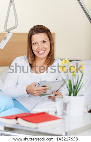 mage of a happy young female patient reading a magazine. Smiling for the camera.