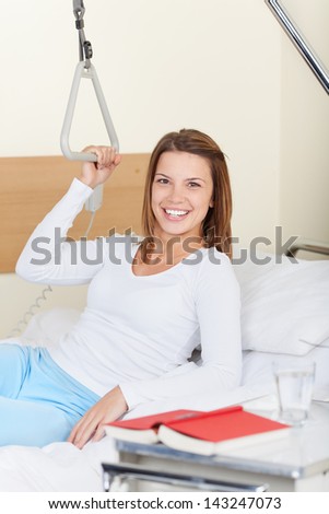Image of a young female lying on the hospital bed and smiling while looking at the camera.