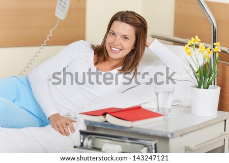 Image of a young female in the hospital, lying on bed and smiling.