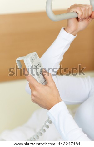 Close-up photograph of a patient adjusting the bed with a remote controller.