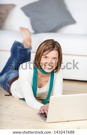 Image Of A Beautiful Young Female Lying On The Floor Of Her Living Room And Working On The Laptop.