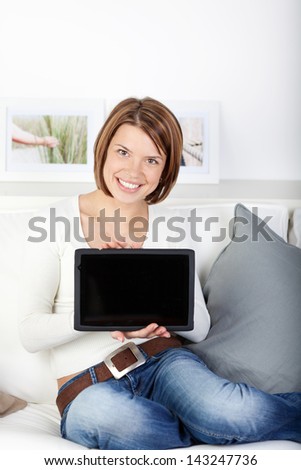 Woman displaying her tablet computer with the blank black screen turned to face the camera for your text or advertisement