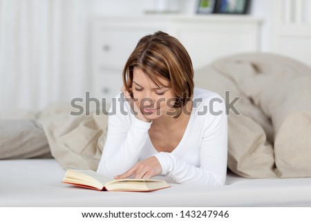 Photograph of a woman reading a book before going to sleep.